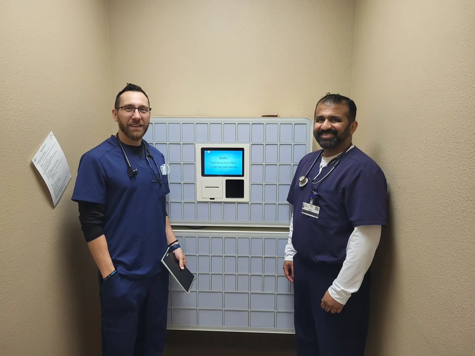 Two clinicians standing next to an in-clinic vending unit in a real deployment