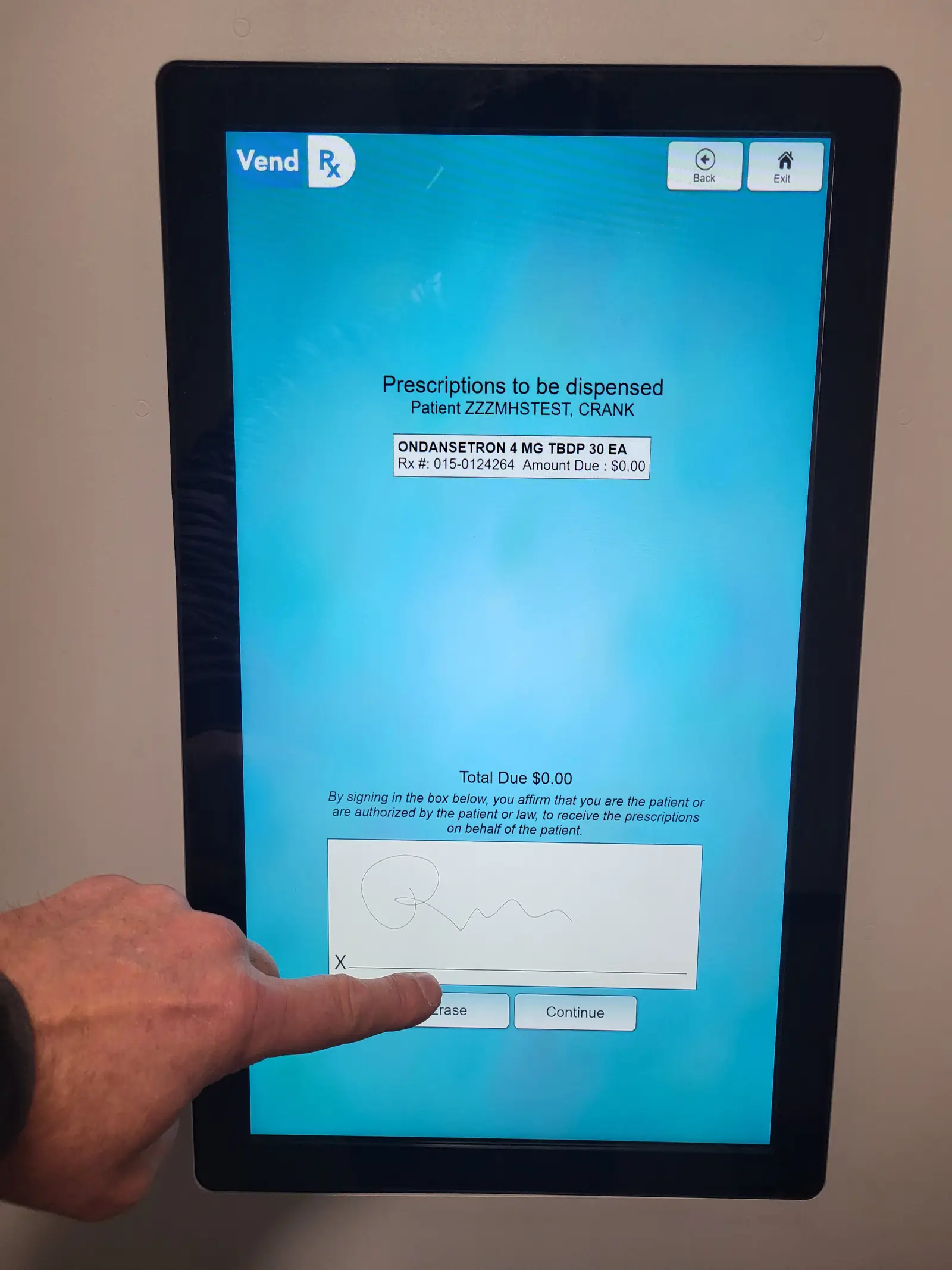 A patient signs for prescriptions on a VendRx unit's touchscreen